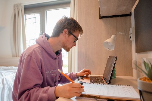 Student sitting at laptop in bedroom